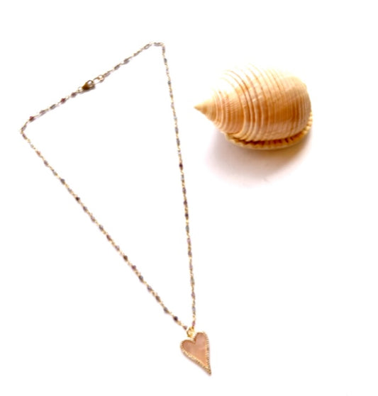 Beaded chain necklace with a pave edged mother of pearl heart pendant beside a spiral shell