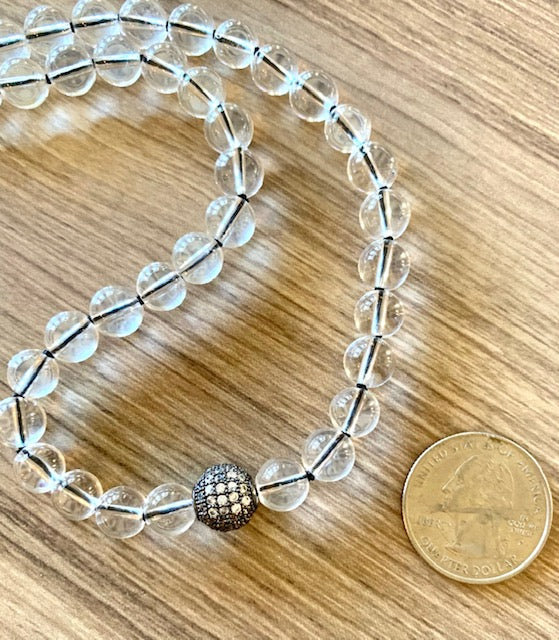 close up of clear crystal quartz mala beads, 8mm, pave cz guru bead, quarter pictured for size comparison