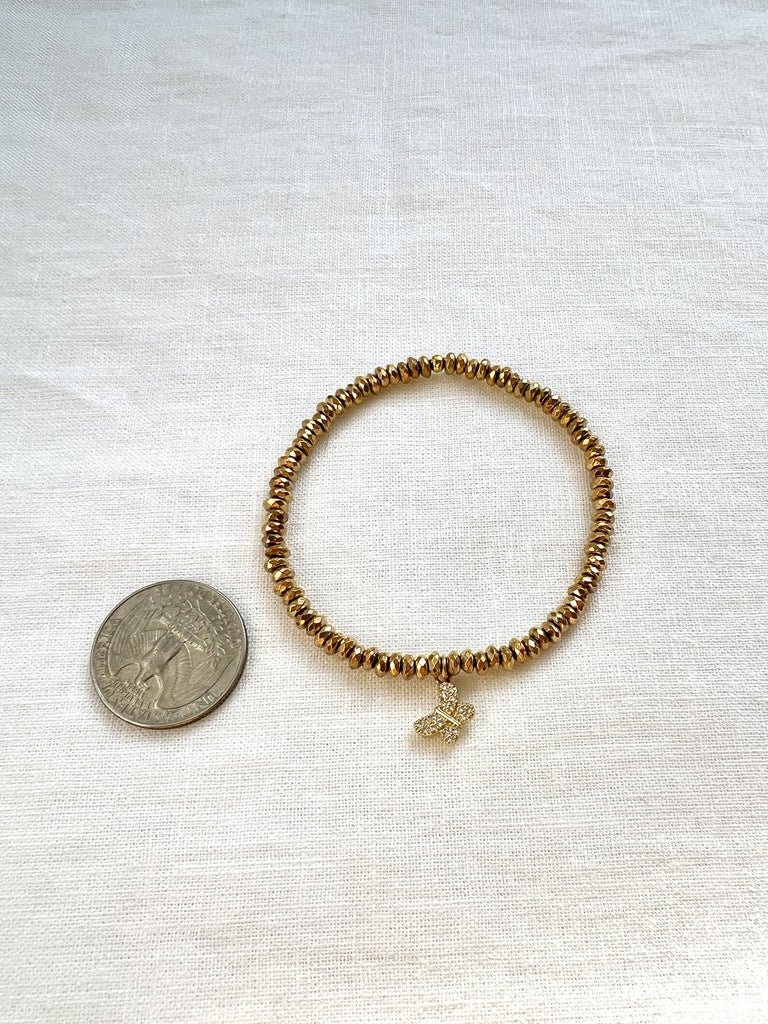 Dainty gold hematite butterfly charm bracelet beside a US quarter for size