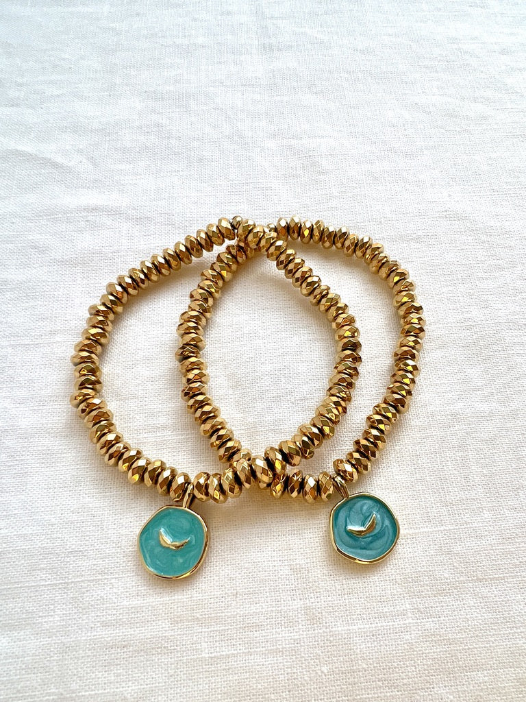 Two Earth Angel gold hematite stretch bracelets, each with an aqua enamel and gold angel wings charm