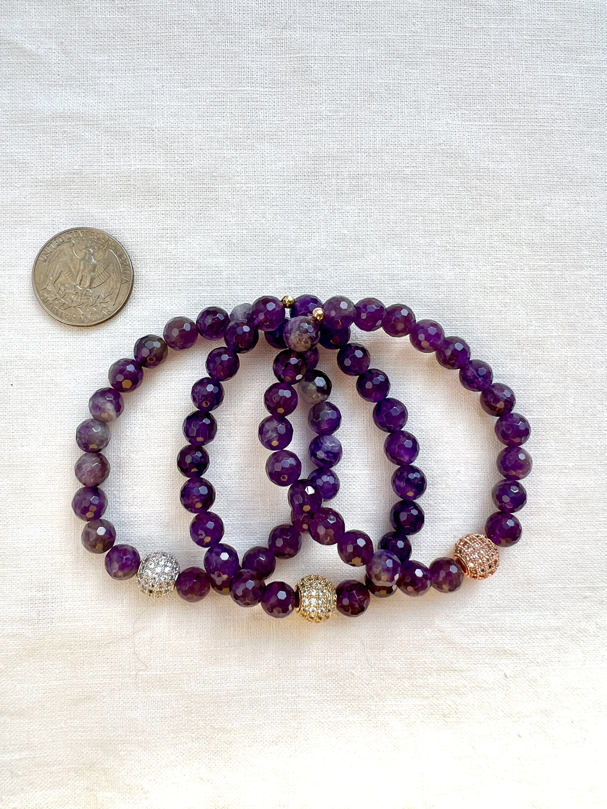 Three faceted amethyst bracelets with silver, gold and rose gold pave beads beside a US quarter for size