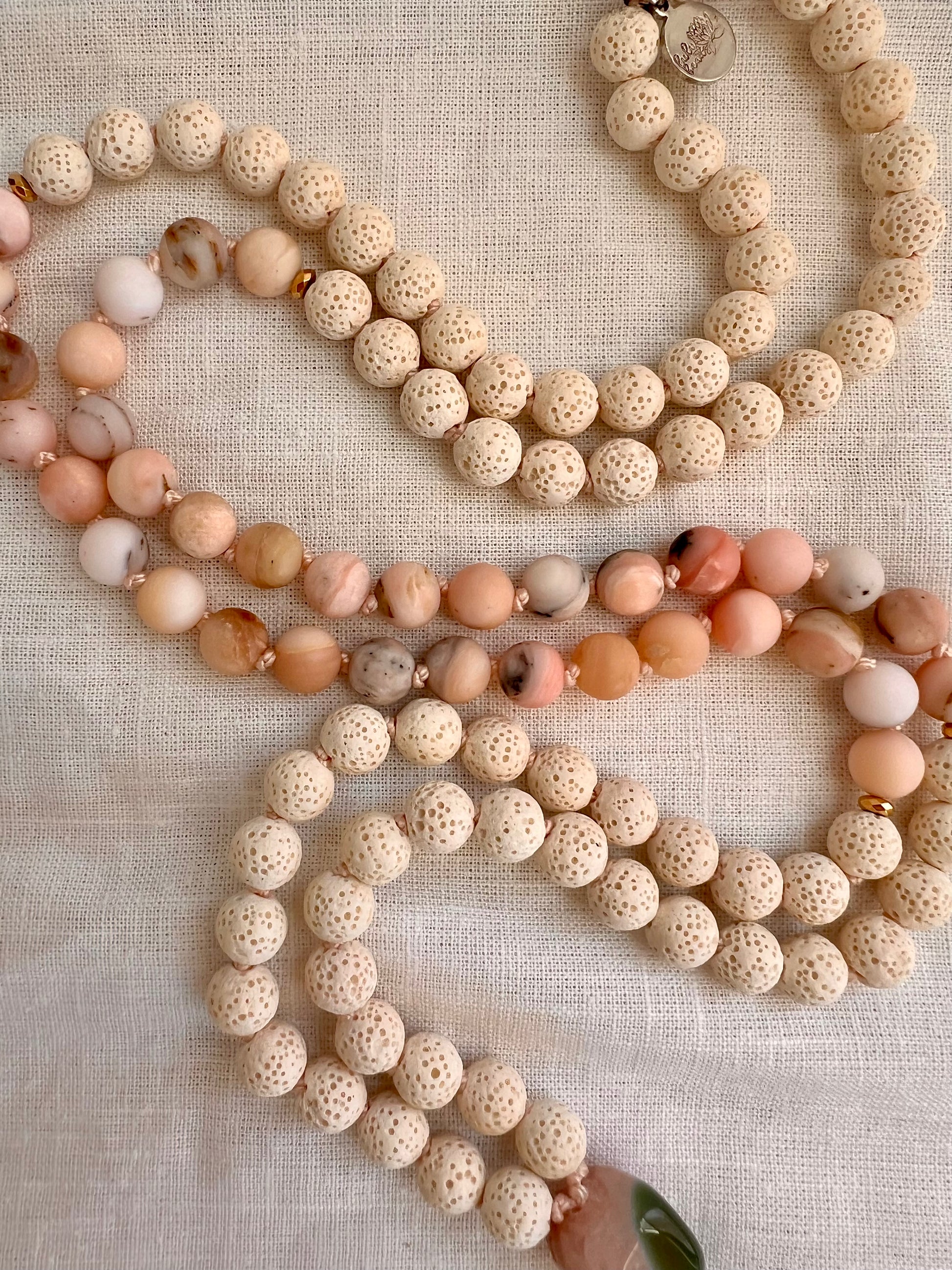 Detail of 8mm white lava and Peruvian pink opal beads with gold plated hematite accent beads on the Blooming Grace Mala necklace