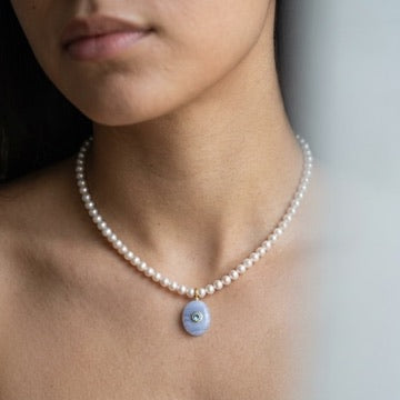 Model wearing the freshwater pearl choker with its blue lace agate and blue topaz pendant resting at the collarbone