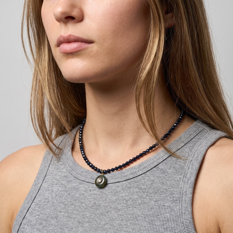 Woman wearing the blue sapphire necklace with a grey tank top, the labradorite pendant resting just below the collarbone