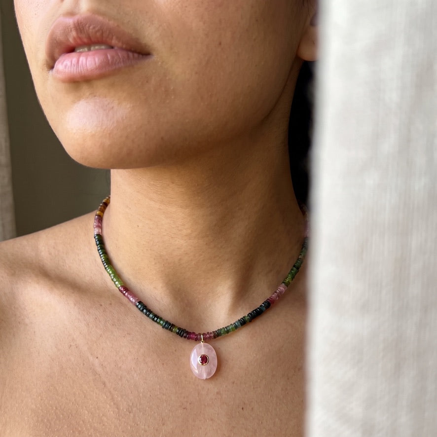 Woman wearing the ombre tourmaline necklace, pink green and blue beads at the base of the neck with the rose quartz pendant hanging below