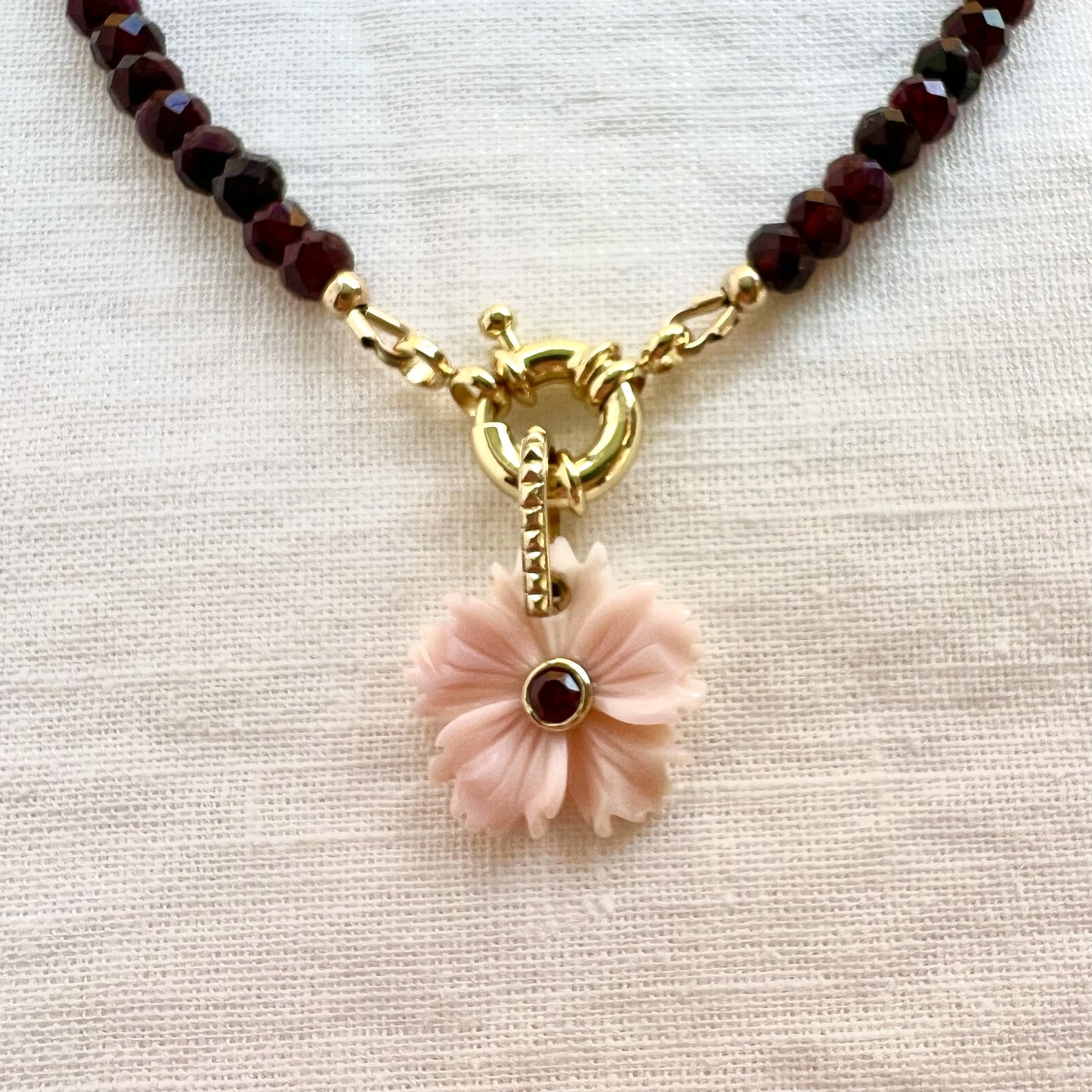 Close view of the gold filled clasp on a garnet choker with a carved pink conch shell flower pendant set with a garnet