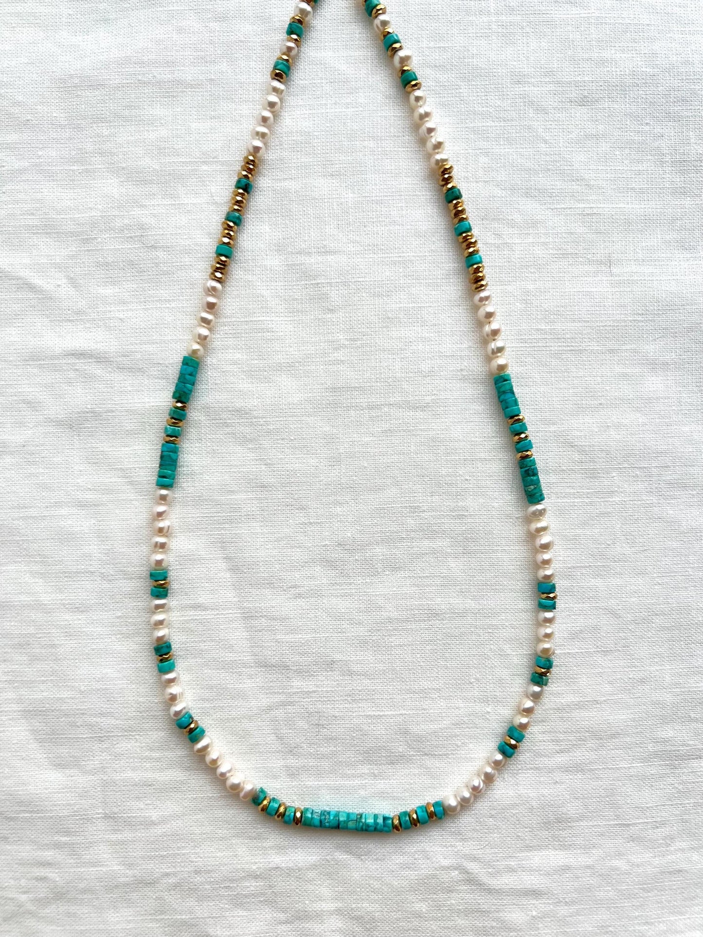 Full length view of the 18 inch strand showing the pattern of Arizona turquoise heishi, round white freshwater pearls and gold plated hematite spacers.