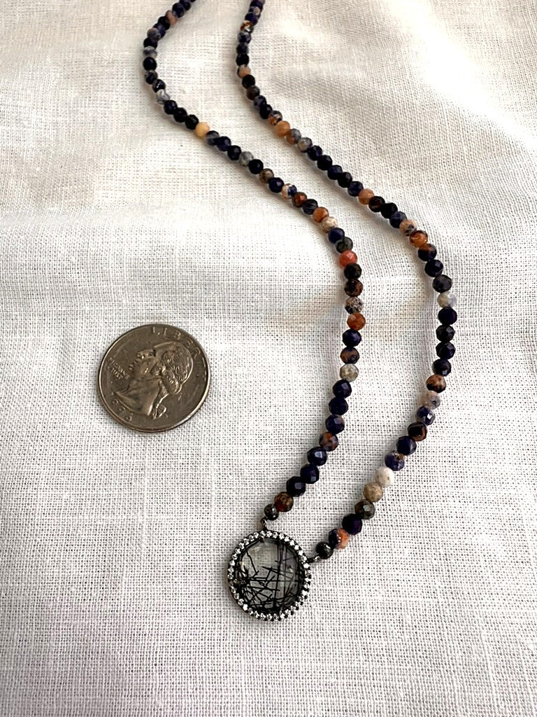 Painted Dusk sodalite and rutilated quartz necklace next to a quarter for scale, showing the 4mm faceted beads and pendant size