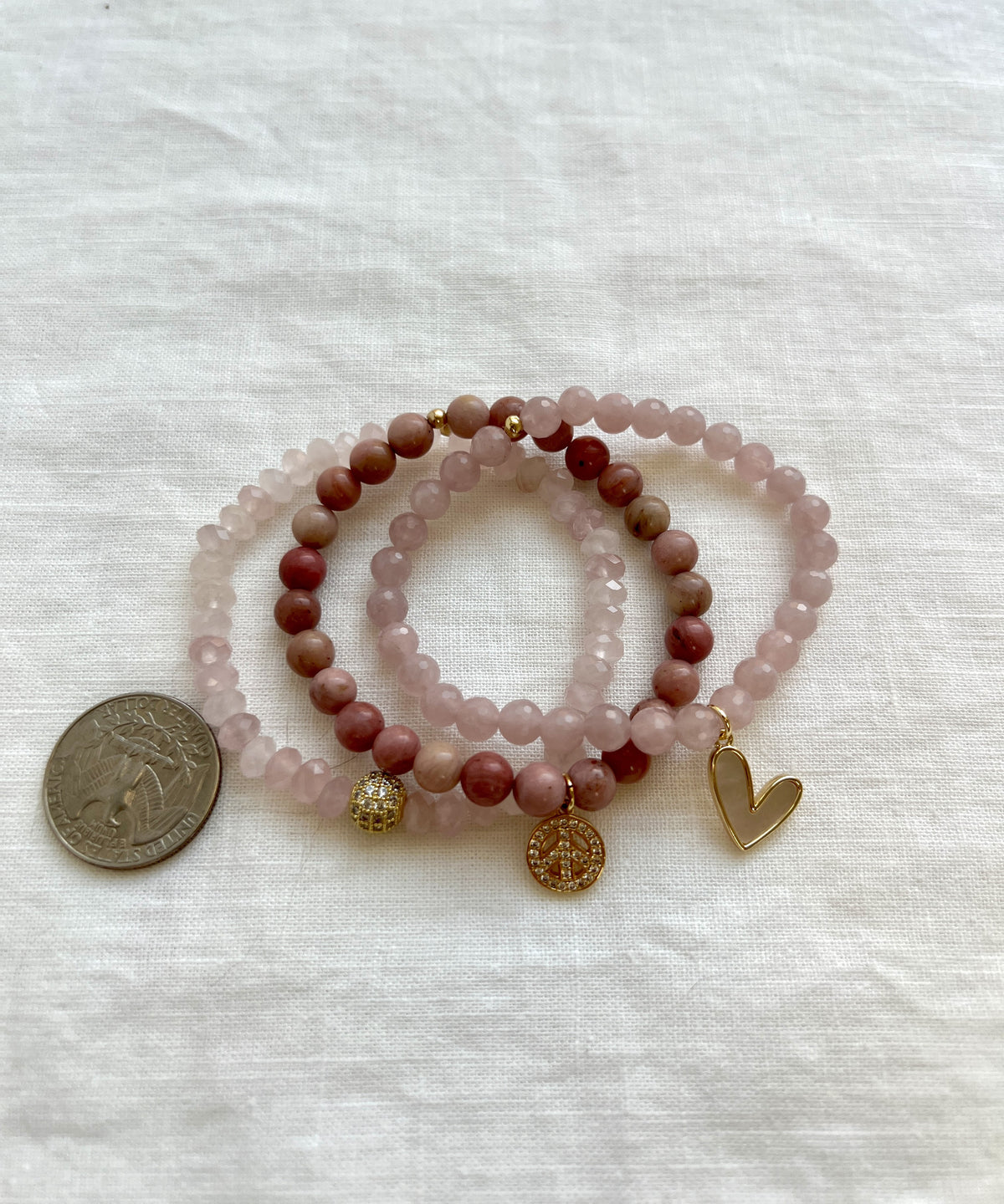 Peace and Love bracelet stack beside a US quarter for scale, showing the 6 mm rose quartz and rhodonite beads