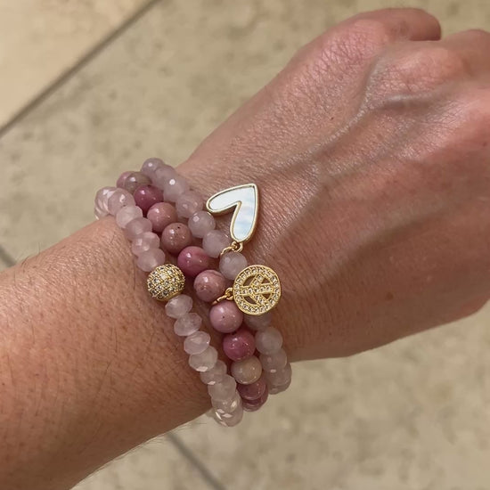 Video of the Peace and Love bracelet stack worn on a wrist, three rose quartz and rhodonite bracelets moving in the light