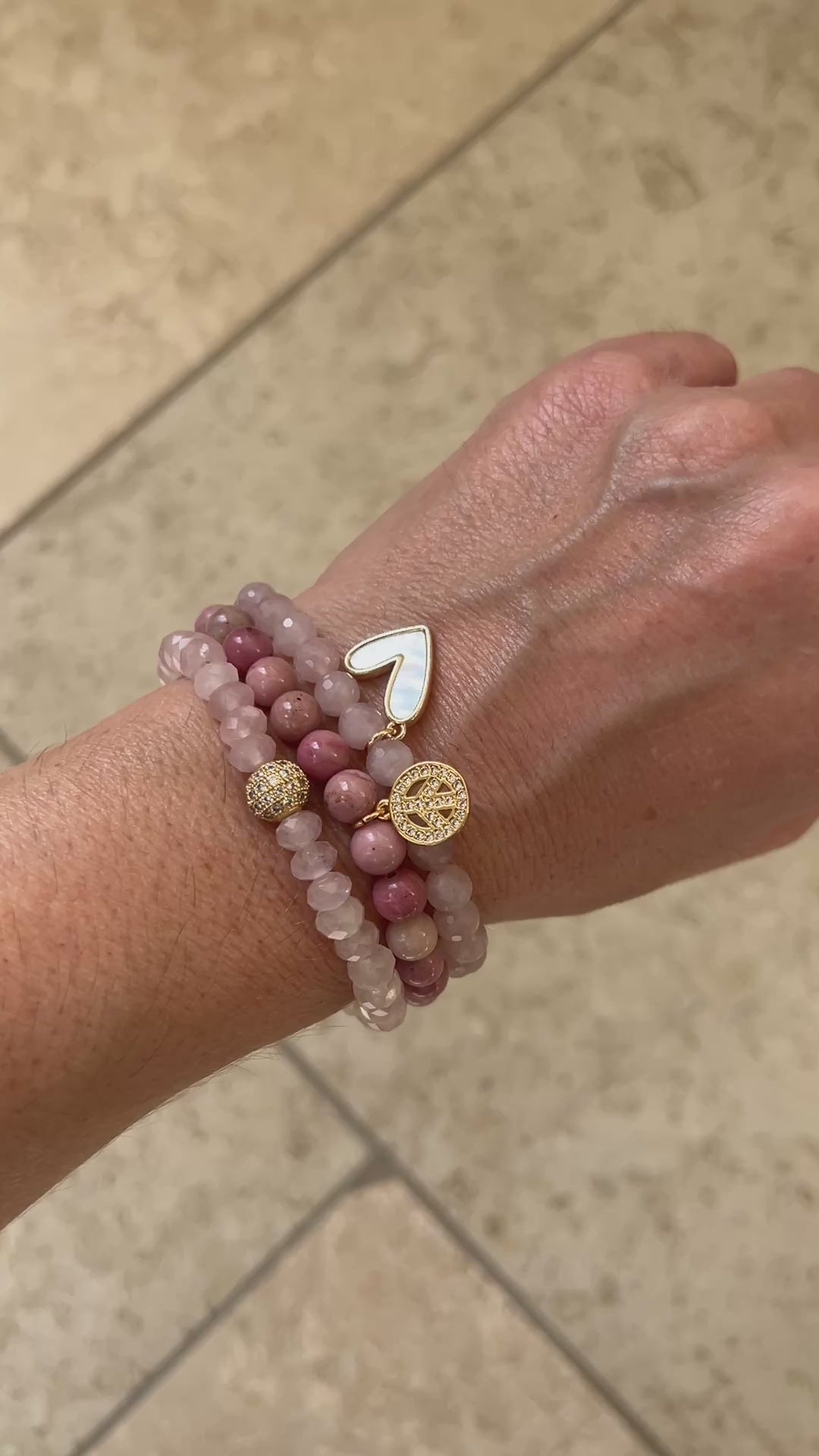 Video of the Peace and Love bracelet stack worn on a wrist, three rose quartz and rhodonite bracelets moving in the light