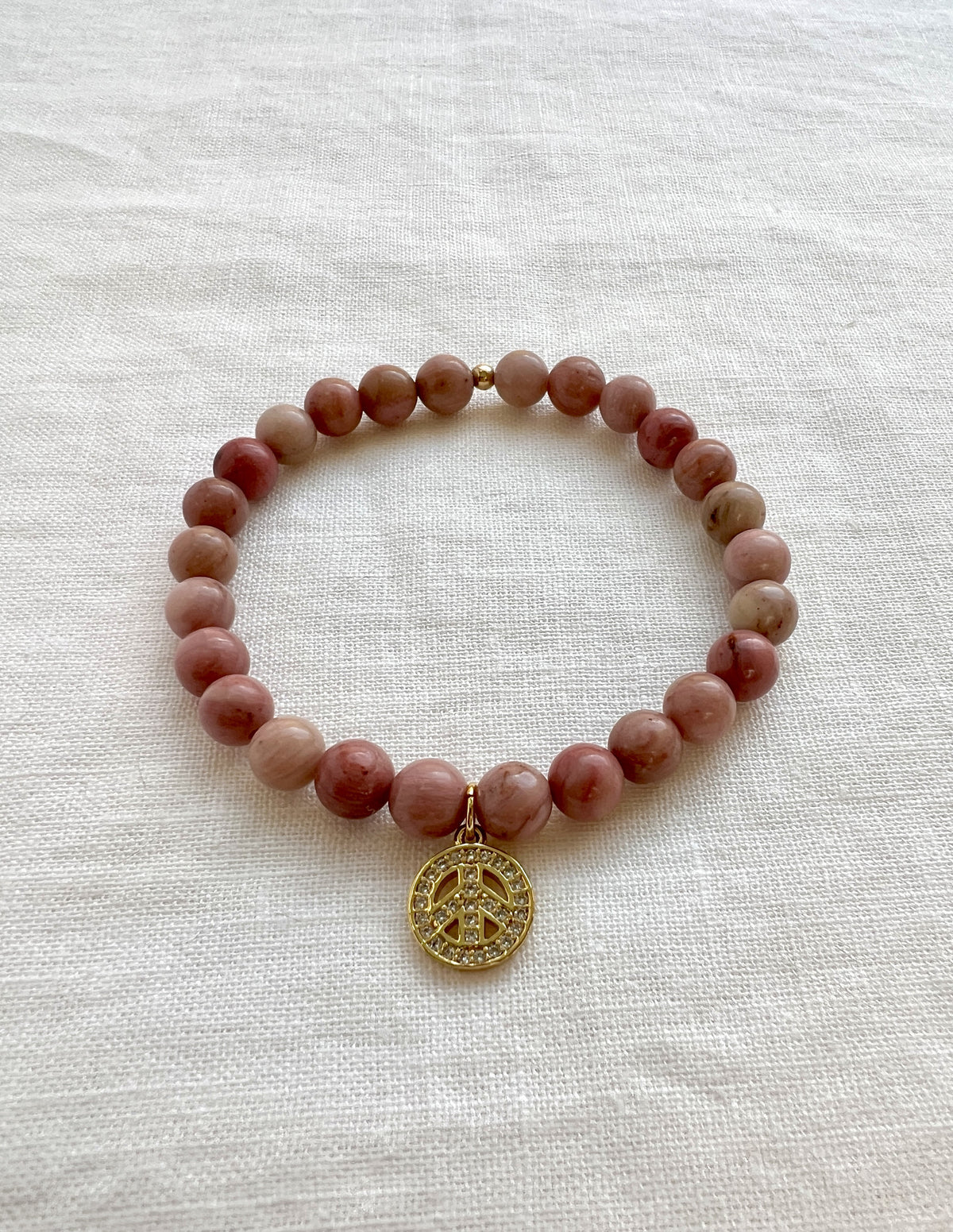 Rhodonite stretch bracelet in rosy red and cream 6 mm beads with a gold plated pave CZ peace charm