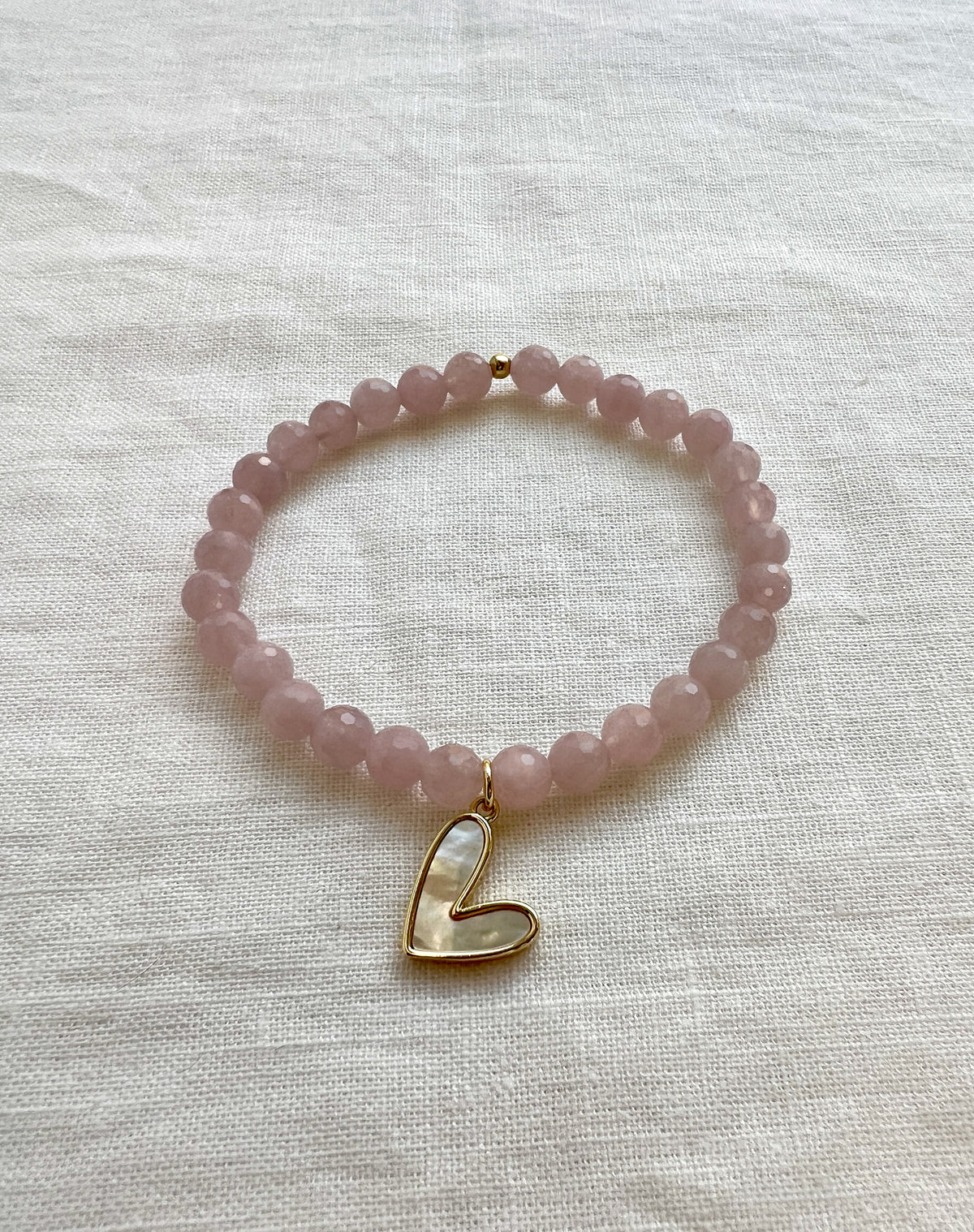 Faceted rose quartz stretch bracelet with a pink mother of pearl heart charm set in gold