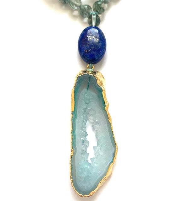 close up of oval laws lazuli guru bead and green agate slice pendant with gold plated edges
