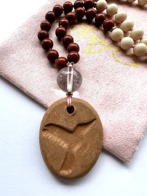 detail of mala necklace terracotta hummingbird oil diffuser pendant and quartz guru bead