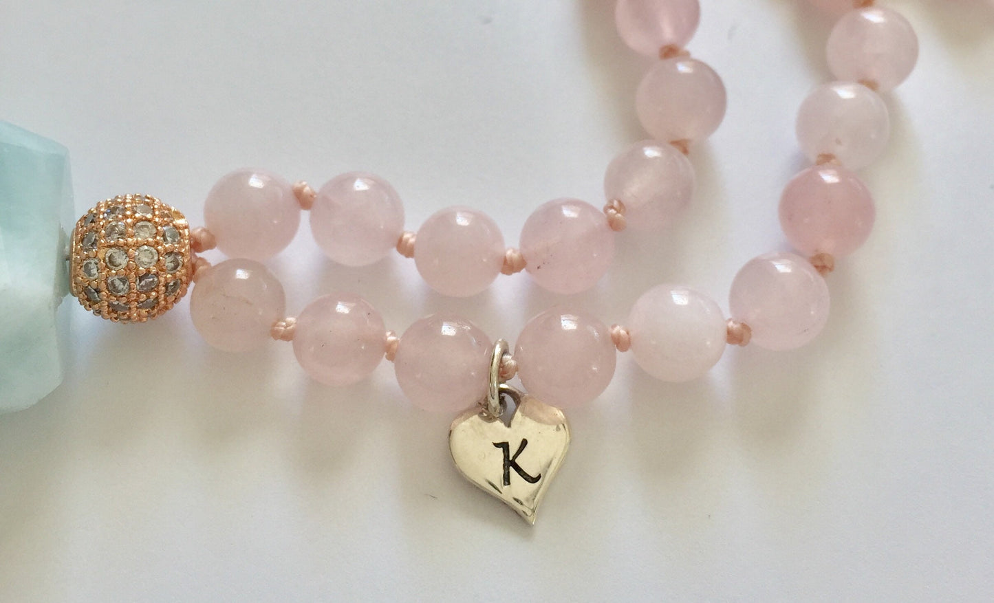 rose quartz mala necklace with rose gold plated guru bead and sterling silver heart shaped K charm
