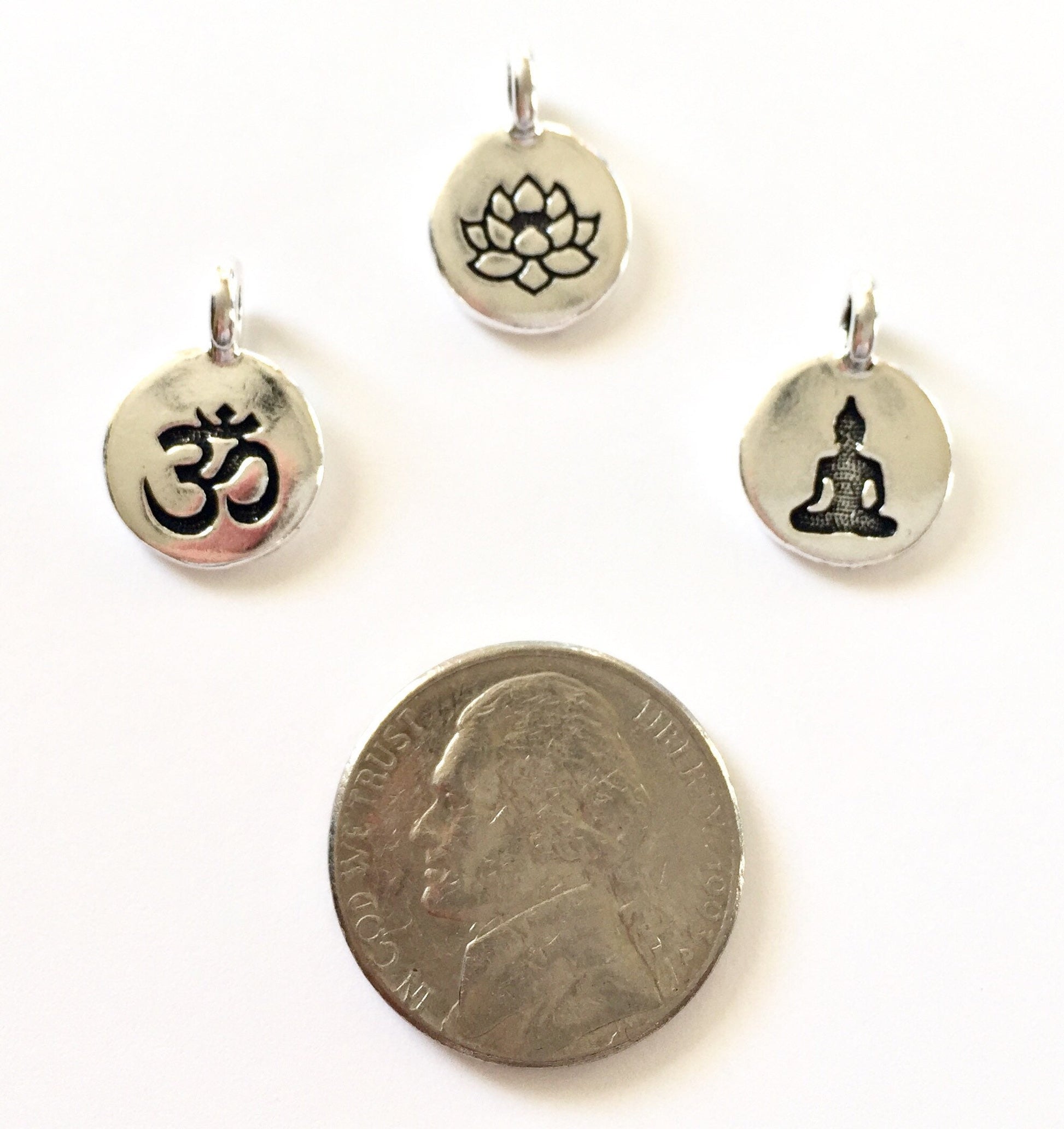 Om, lotus and buddha charms with a nickel for size comparison