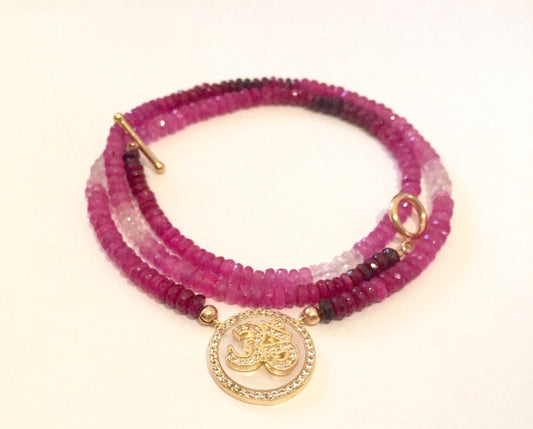 Coiled ruby and pink sapphire ombre necklace with a pave Om medallion and a gold toggle clasp