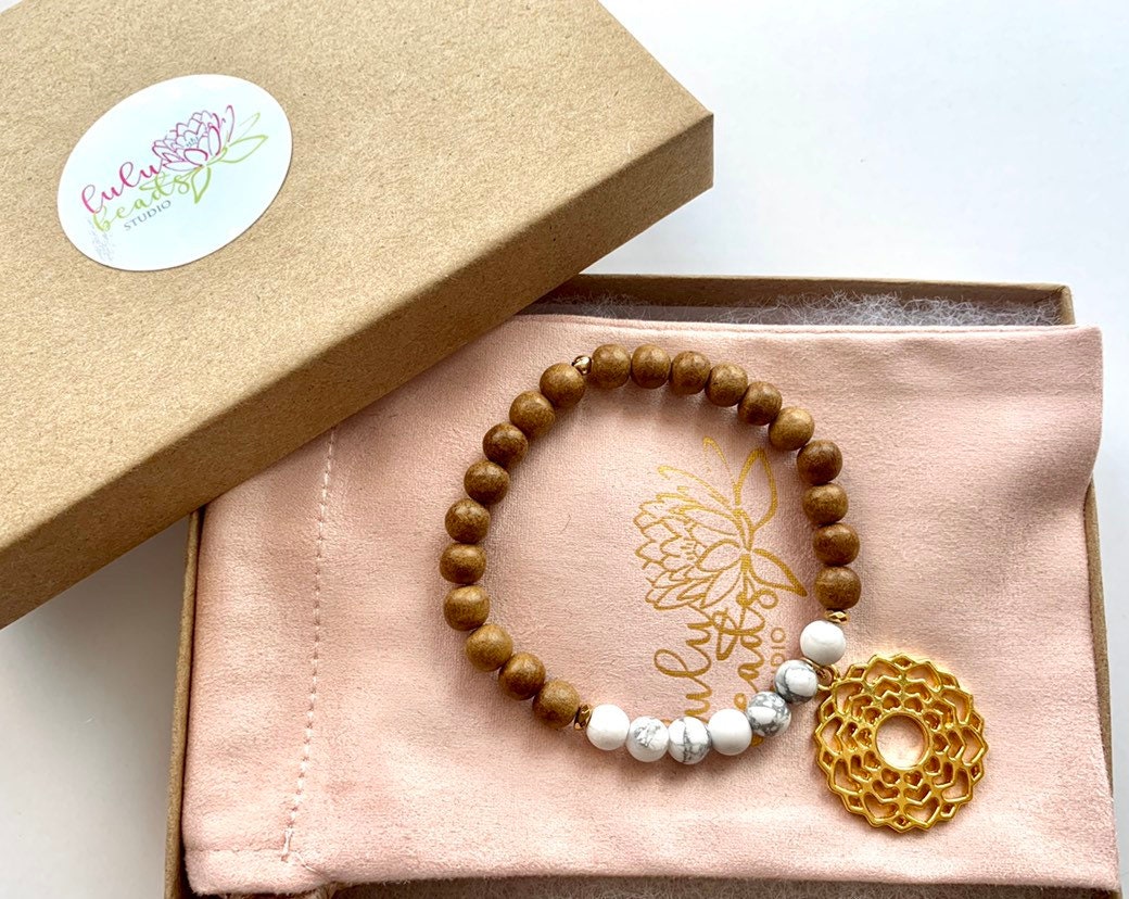 Sandalwood and howlite jasper bracelet with gold toned crown chakra charm, strung on stretch cord in gift box with jewelry pouch