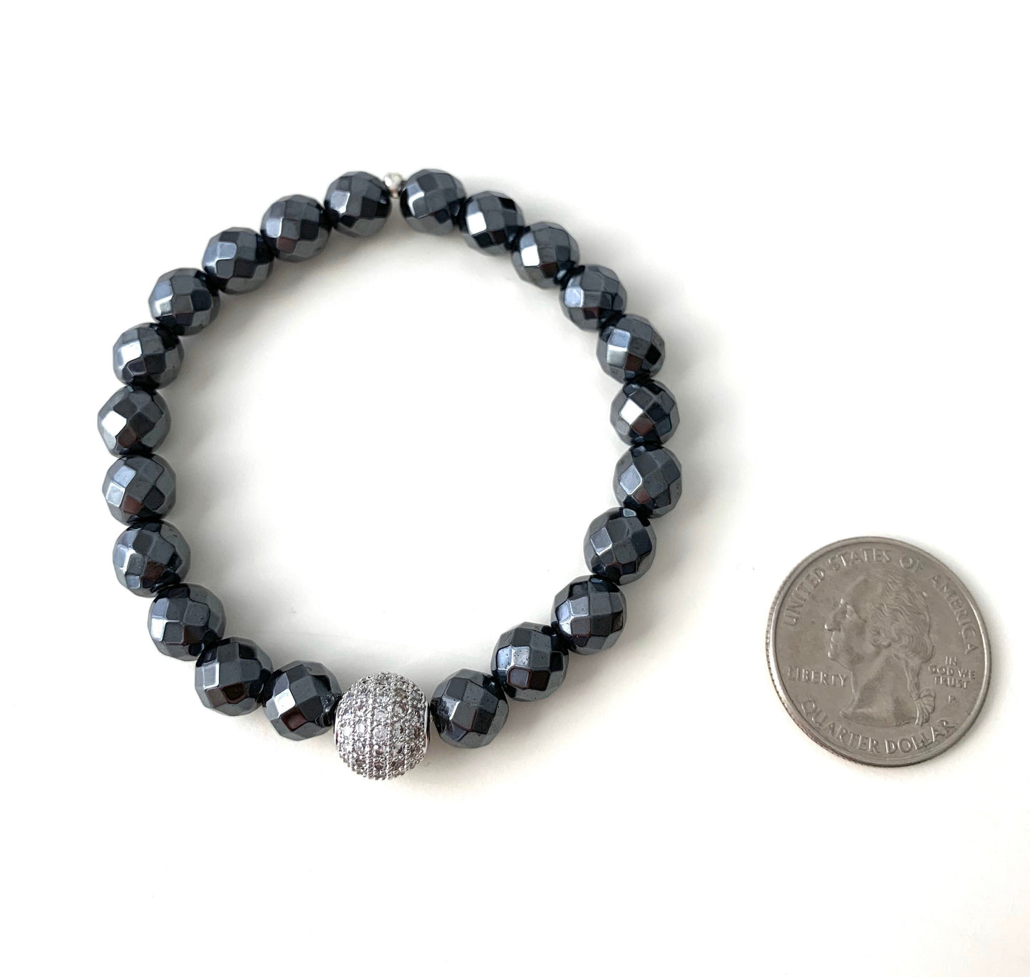 8mm faceted hematite bracelet with pave cz guru bead .  next to a quarter for size comparison