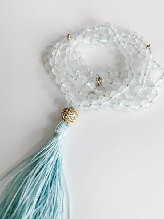 Coiled rainbow moonstone mala with a pale blue silk tassel and a cubic zirconia guru bead