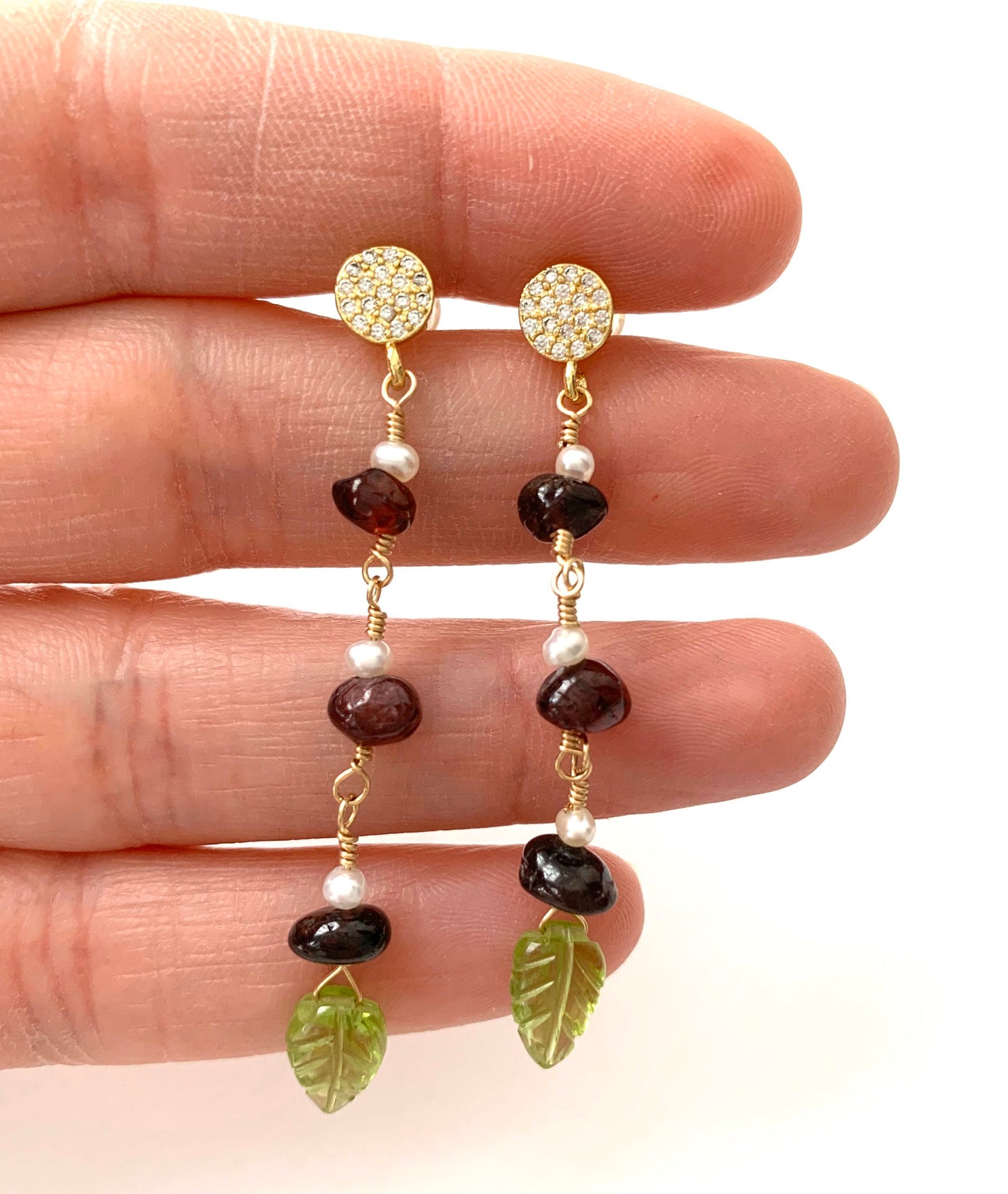 yellow gold filled dangle earring with pave' cz round studs and 3 garnet and pearl stations suspended from chain. carved peridot leaves hang from the bottom.  