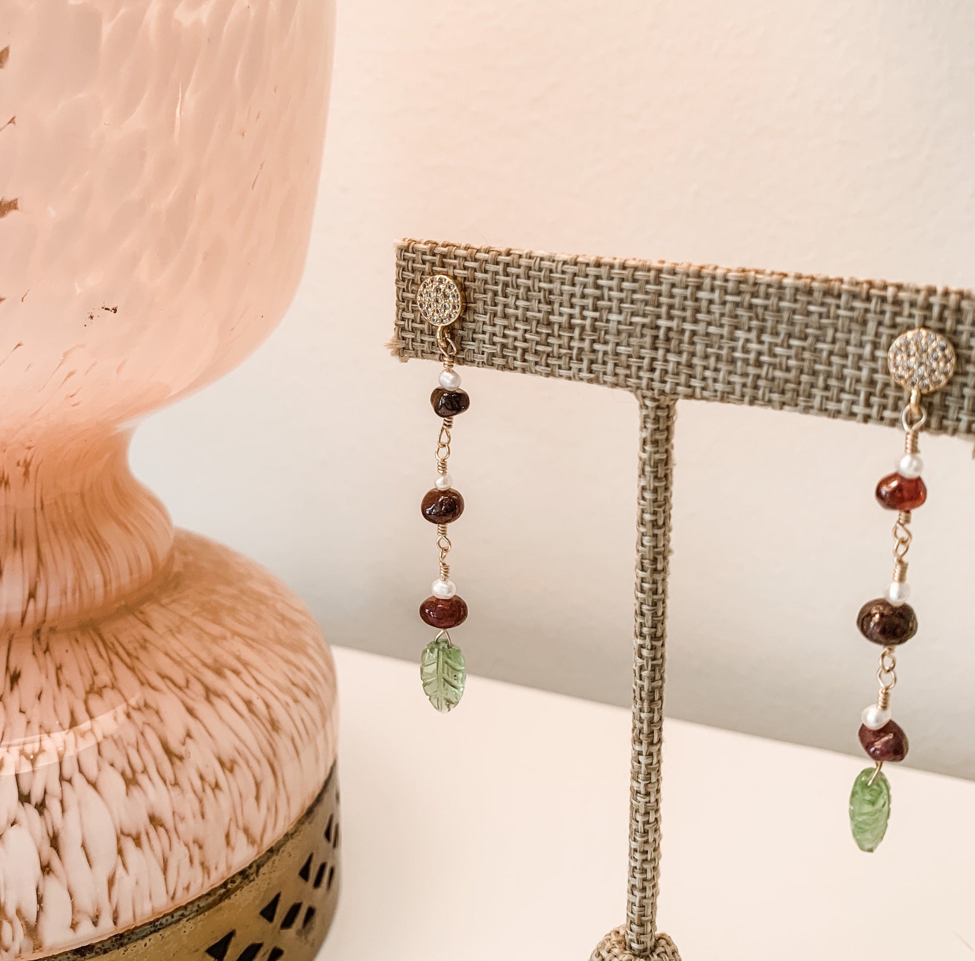 yellow gold filled dangle earring with pave' cz round studs and 3 garnet and pearl stations suspended from chain. carved peridot leaves hang from the bottom.  